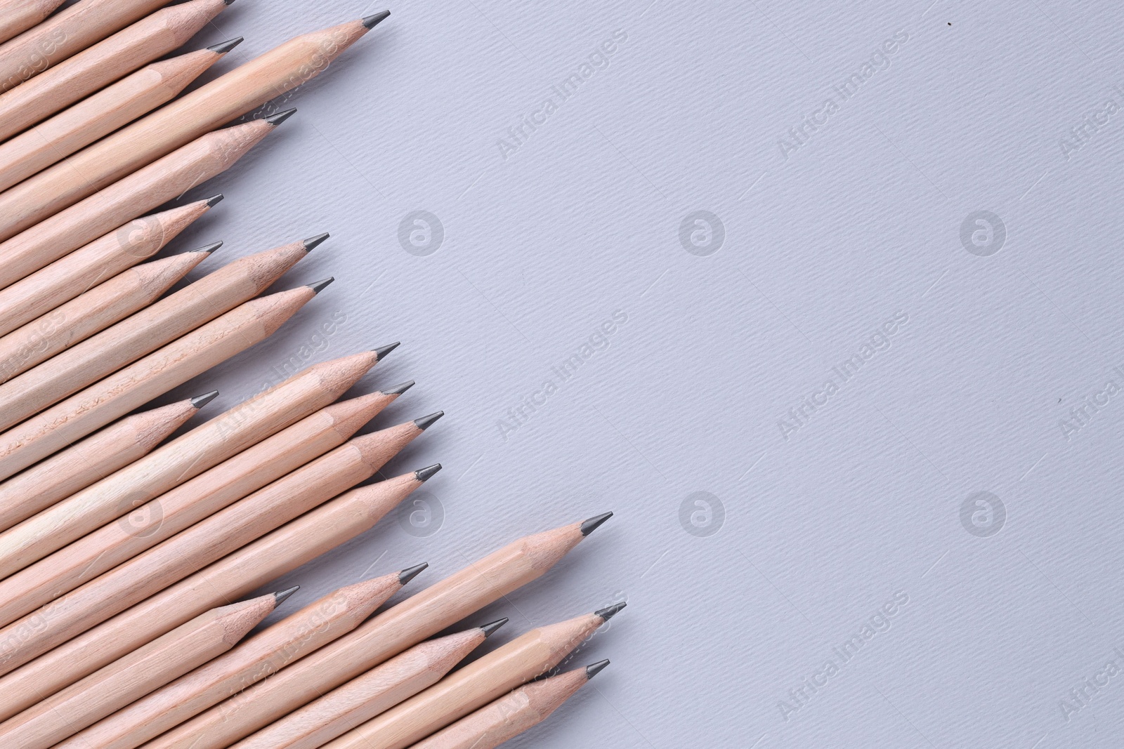 Photo of Many pencils on light grey background, top view. Space for text