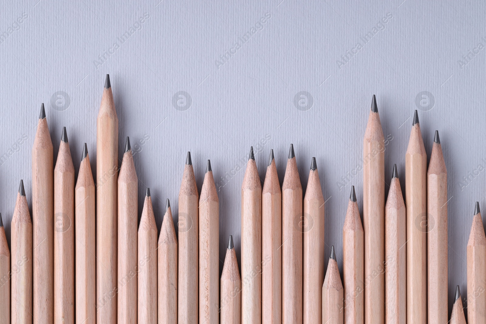 Photo of Many pencils on light grey background, top view. Space for text