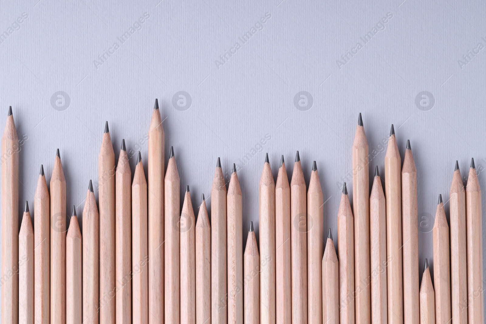 Photo of Many pencils on light grey background, top view. Space for text