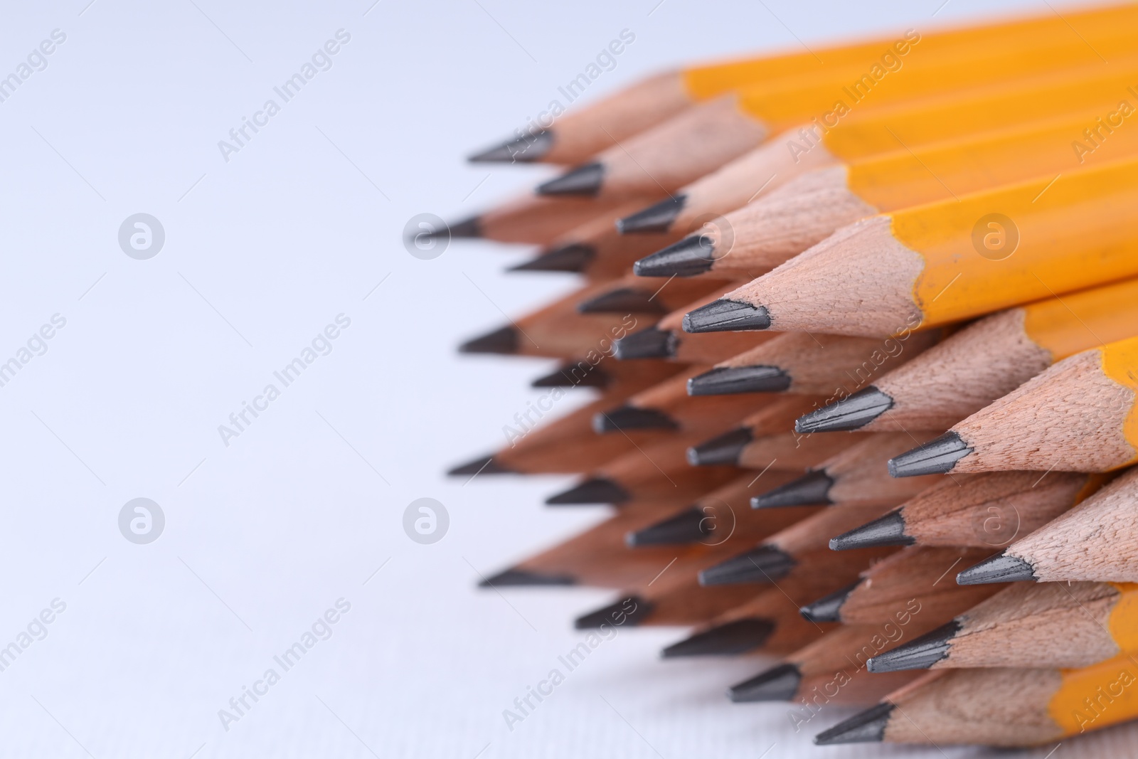 Photo of Many pencils on light grey background, closeup. Space for text