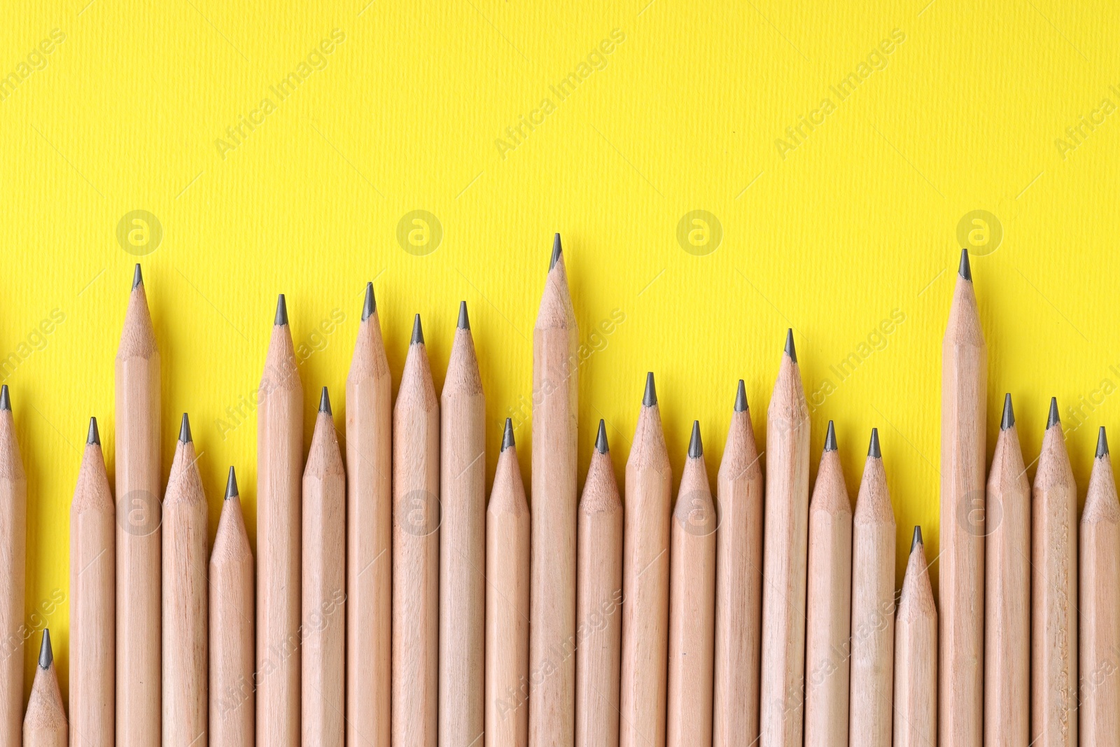 Photo of Many pencils on yellow background, top view