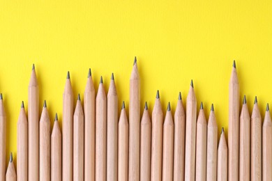 Photo of Many pencils on yellow background, top view