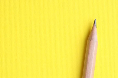 Photo of One pencil on yellow background, top view. Space for text