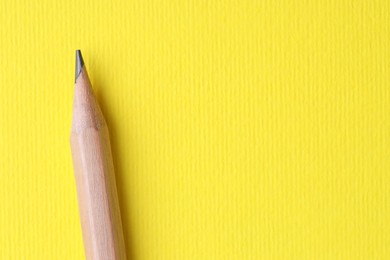 Photo of One pencil on yellow background, top view. Space for text