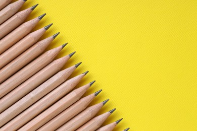 Photo of Many pencils on yellow background, top view. Space for text