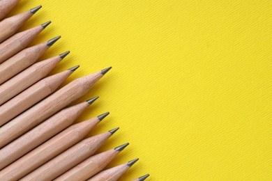 Photo of Many pencils on yellow background, top view. Space for text