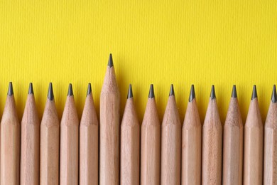 Photo of Many pencils on yellow background, top view. Space for text