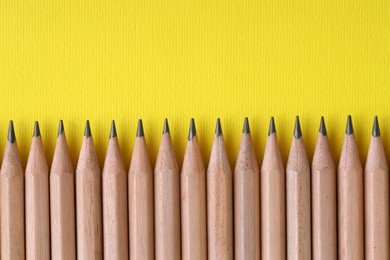 Photo of Many pencils on yellow background, top view. Space for text