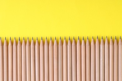 Photo of Many pencils on yellow background, top view. Space for text