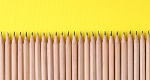 Photo of Many pencils on yellow background, top view. Space for text