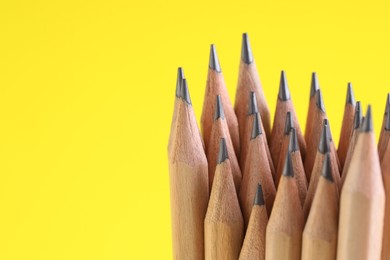 Photo of Many graphite pencils on yellow background, closeup. Space for text