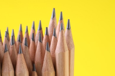 Photo of Many graphite pencils on yellow background, closeup