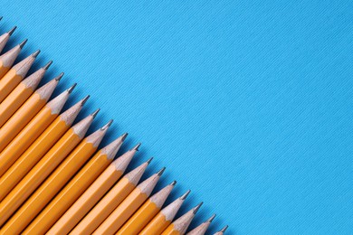 Photo of Many pencils on light blue background, top view. Space for text