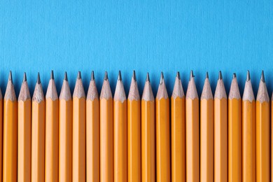 Photo of Many pencils on light blue background, top view. Space for text