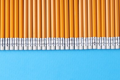 Photo of Many pencils on light blue background, top view. Space for text