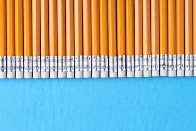 Photo of Many pencils on light blue background, top view. Space for text