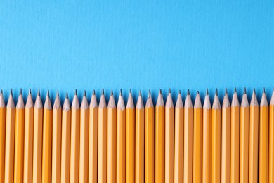 Photo of Many pencils on light blue background, top view. Space for text