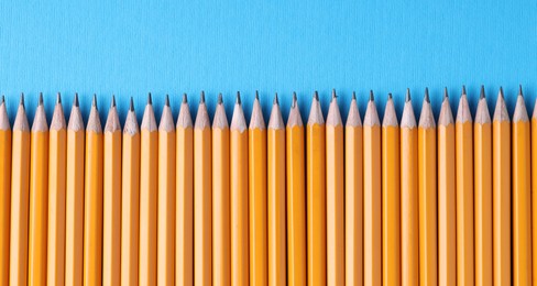 Photo of Many pencils on light blue background, top view. Space for text