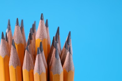 Many pencils on light blue background, closeup. Space for text