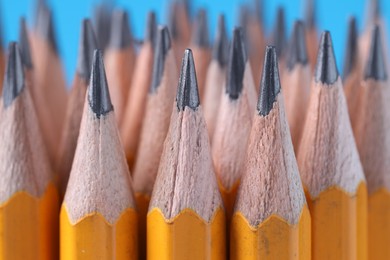 Photo of Many pencils on light blue background, closeup