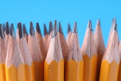 Photo of Many pencils on light blue background, closeup