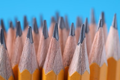 Photo of Many pencils on light blue background, closeup