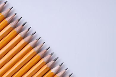 Photo of Many pencils on light grey background, top view. Space for text