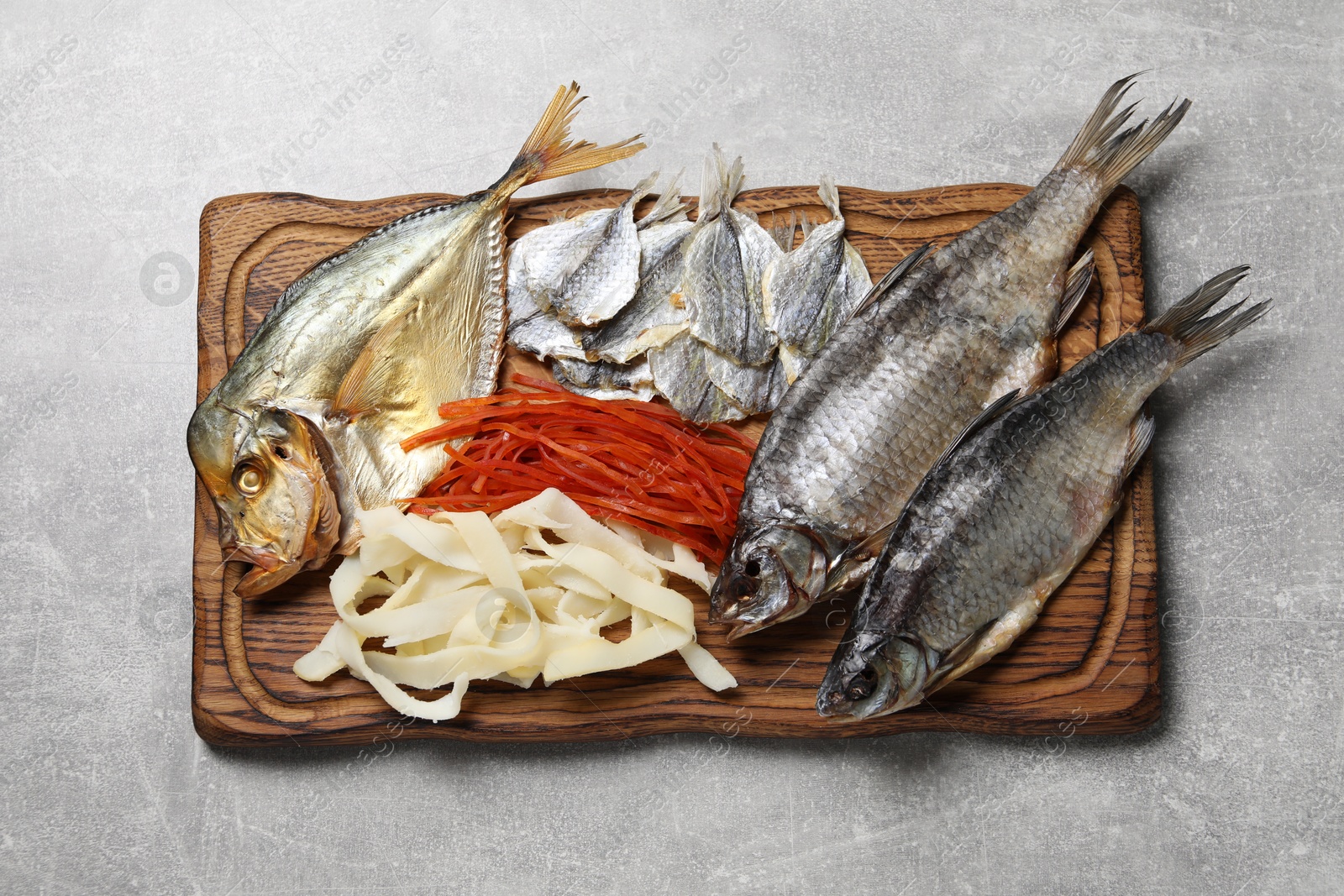 Photo of Many different dried fish snacks on light grey table, top view