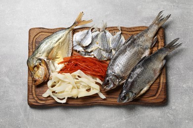 Photo of Many different dried fish snacks on light grey table, top view