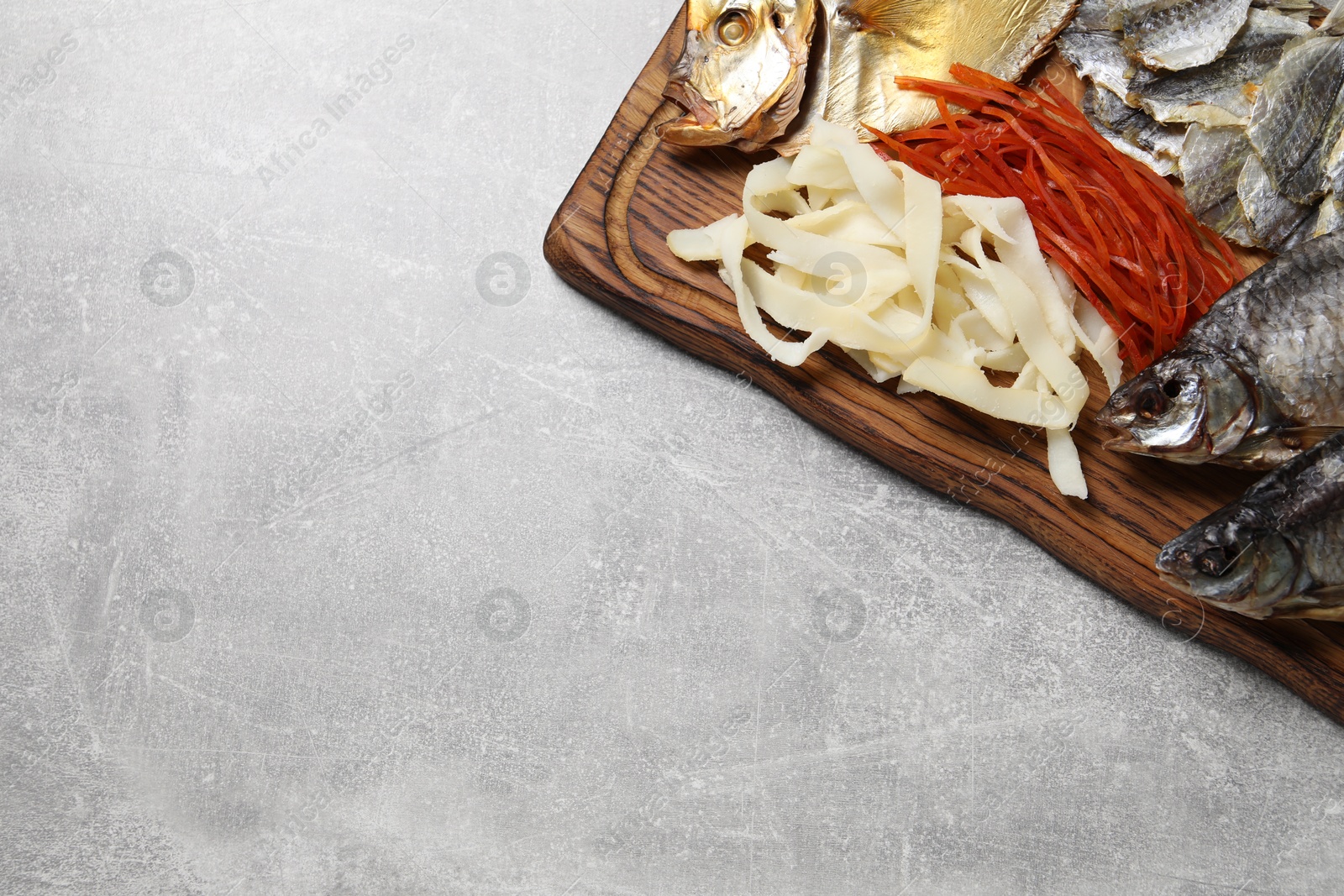 Photo of Many different dried fish snacks on light grey table, top view. Space for text