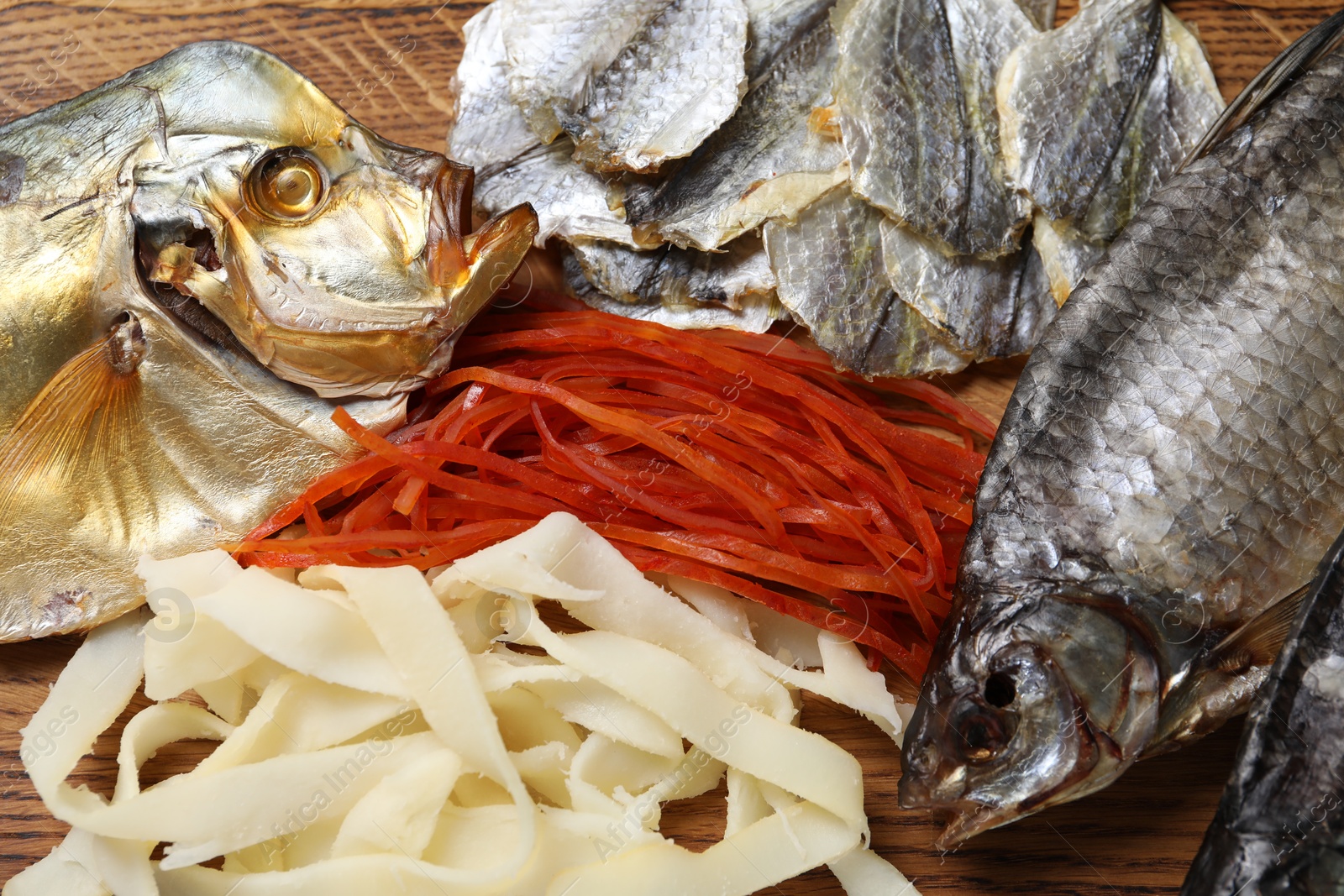 Photo of Many different dried fish snacks on wooden table, closeup