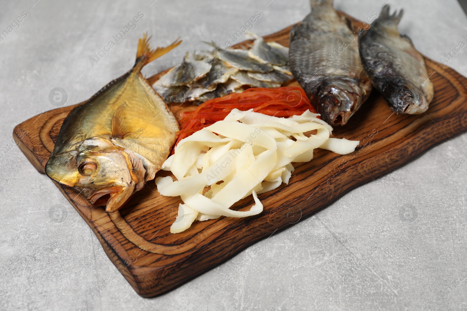 Photo of Many different dried fish snacks on light grey table, closeup