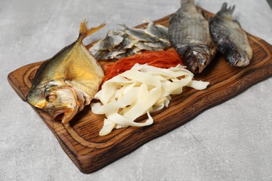 Many different dried fish snacks on light grey table, closeup