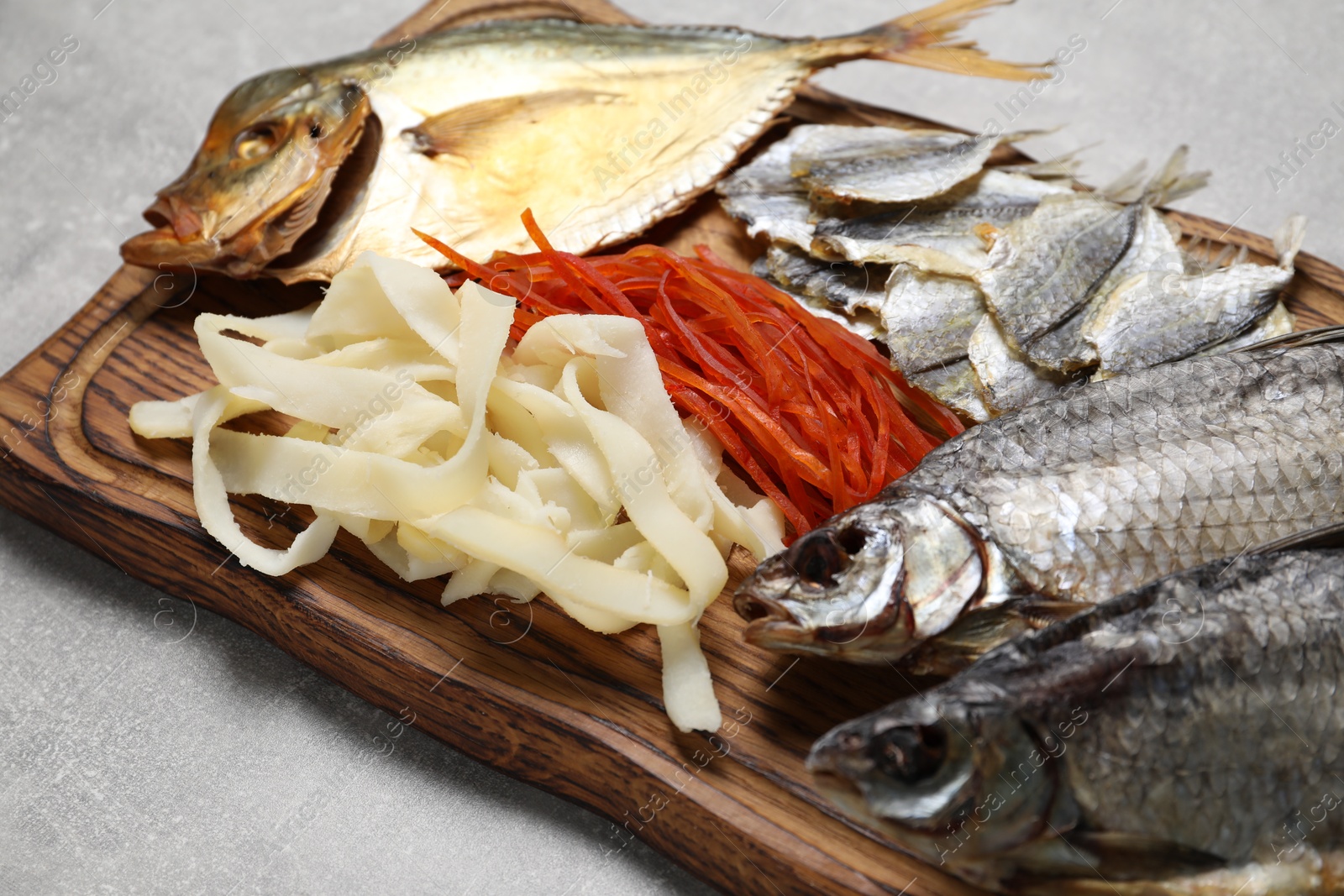 Photo of Many different dried fish snacks on light grey table, closeup