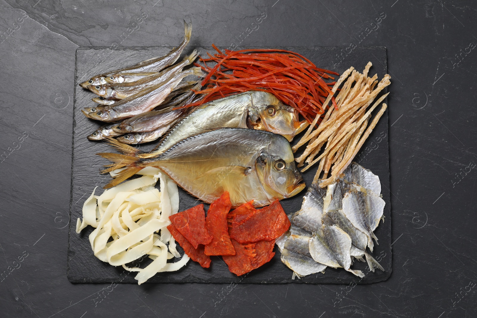 Photo of Many different dried fish snacks on black table, top view