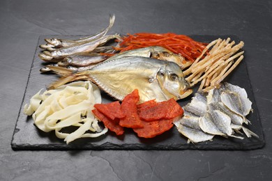 Photo of Many different dried fish snacks on black table