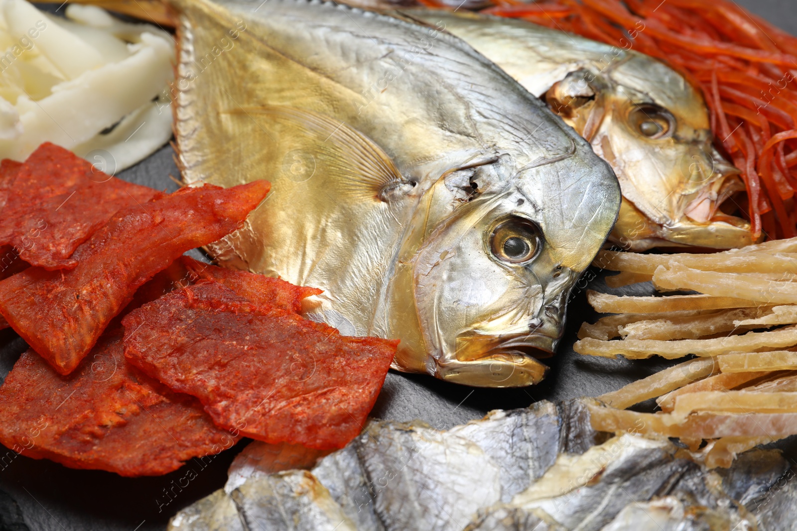 Photo of Many different dried fish snacks on black table, closeup