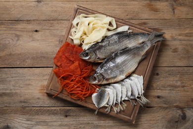 Many different dried fish snacks on wooden table, top view