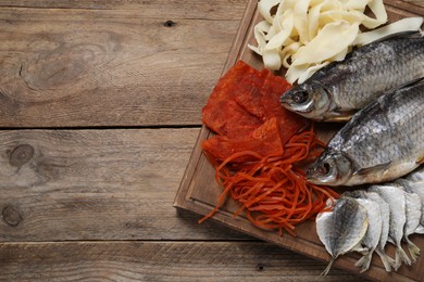 Photo of Many different dried fish snacks on wooden table, top view. Space for text