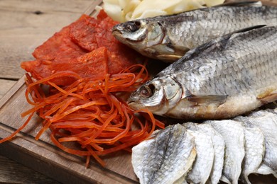 Photo of Many different dried fish snacks on wooden table, closeup