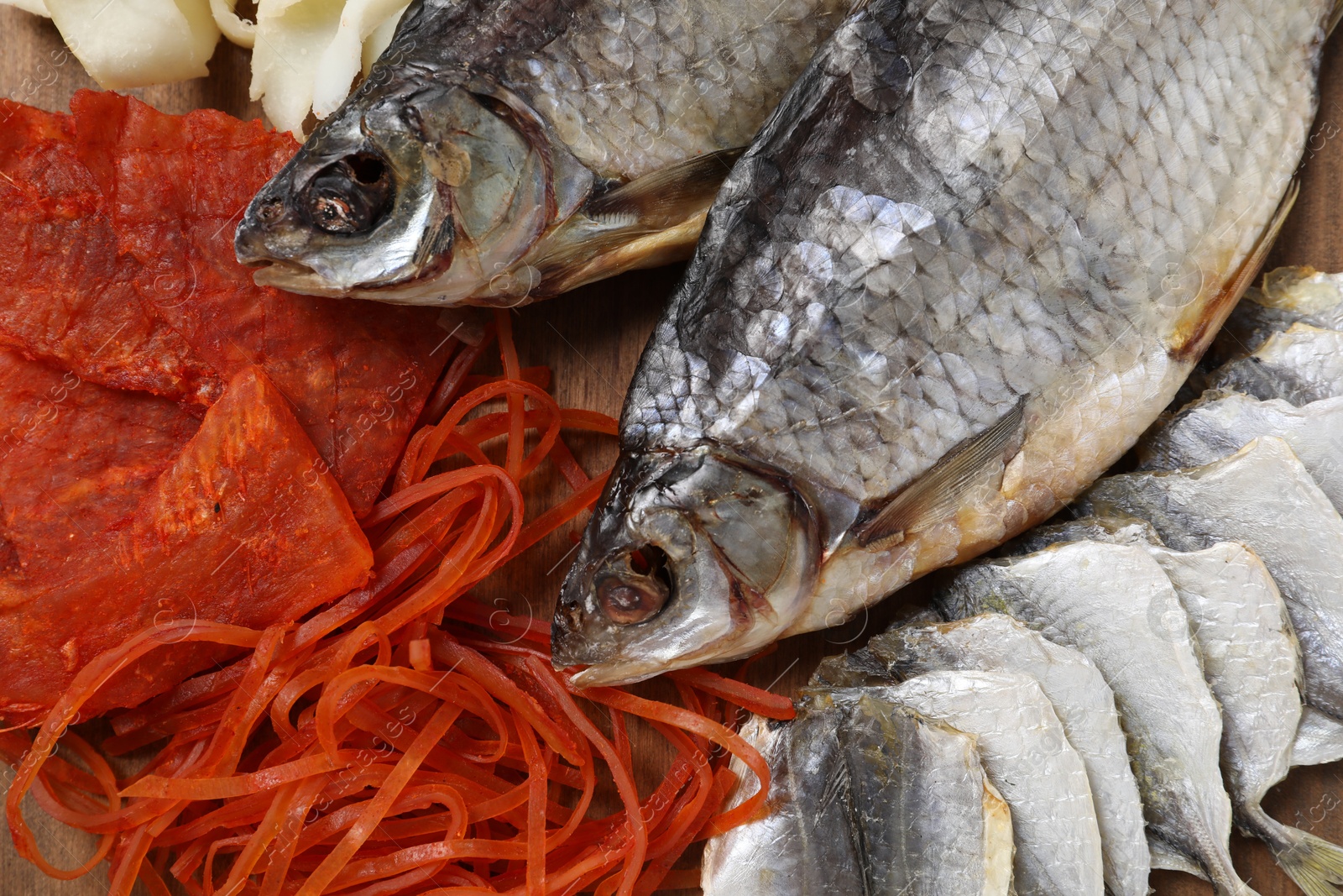 Photo of Many different dried fish snacks on wooden table, closeup