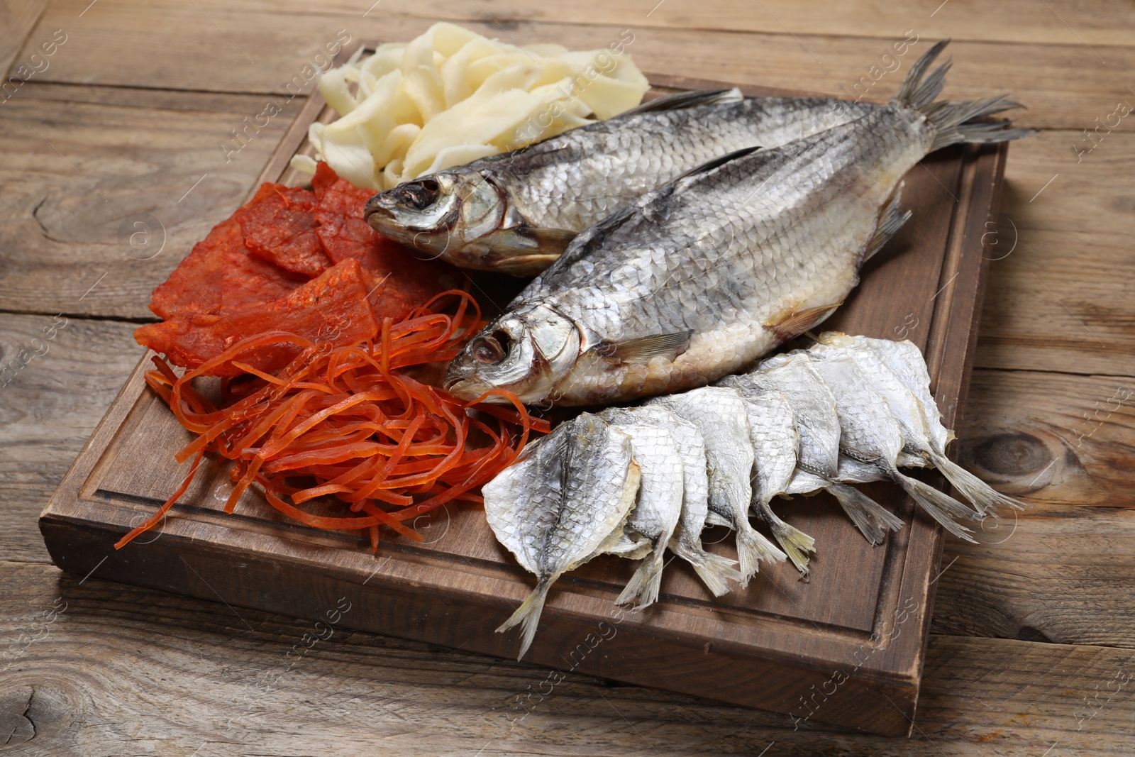 Photo of Many different dried fish snacks on wooden table, closeup