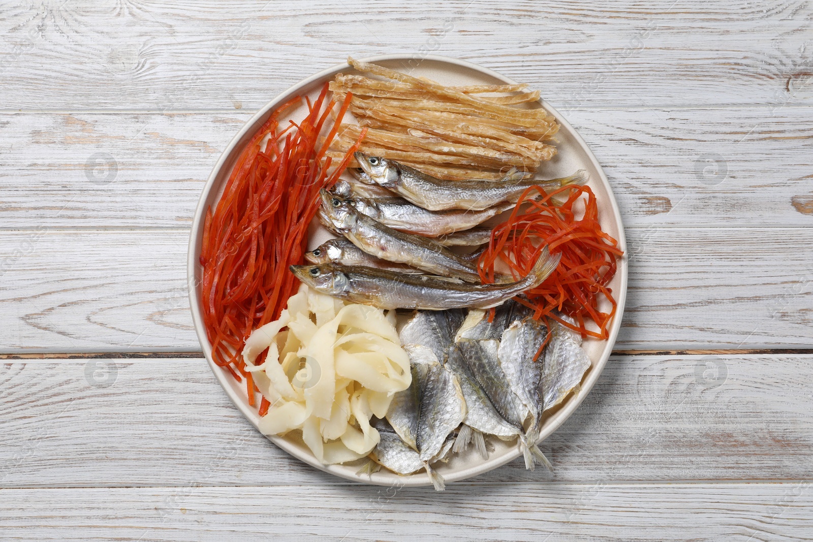 Photo of Many different dried fish snacks on white wooden table, top view