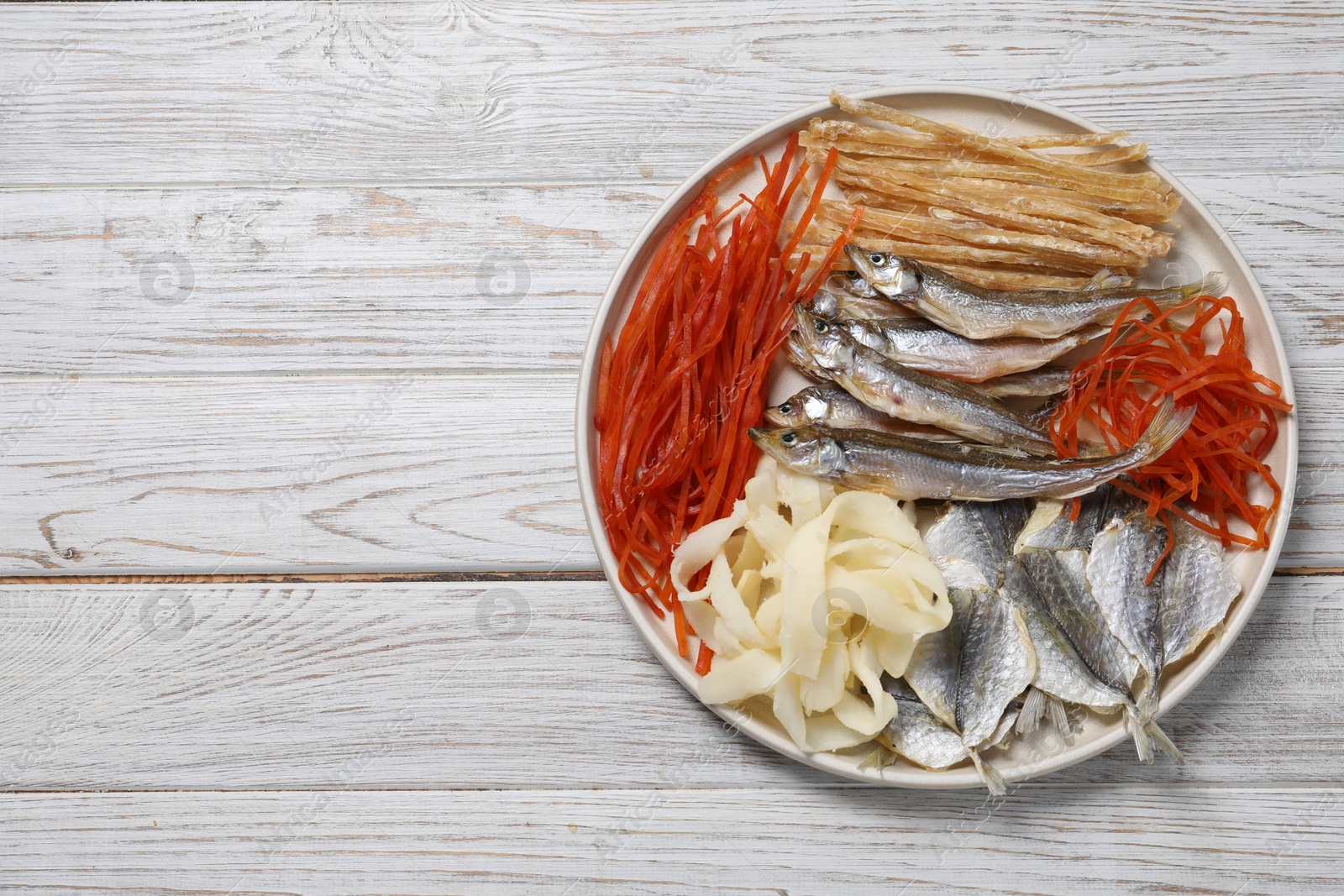 Photo of Many different dried fish snacks on white wooden table, top view. Space for text