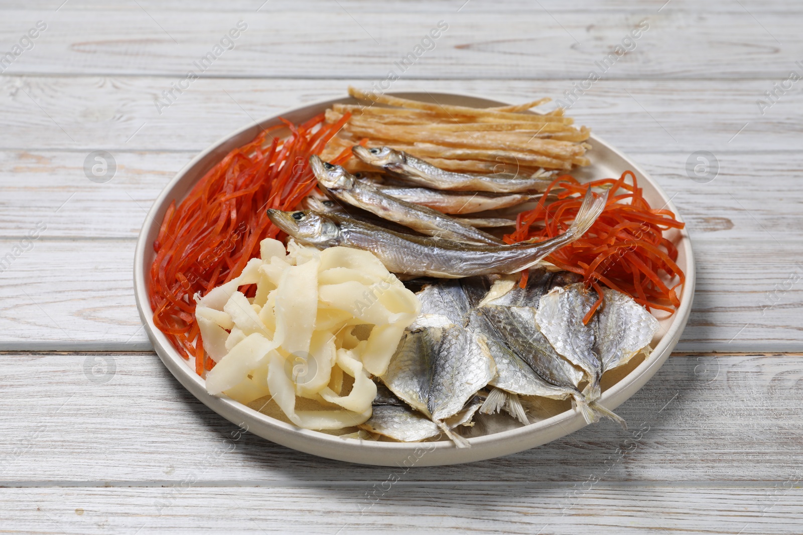 Photo of Many different dried fish snacks on white wooden table