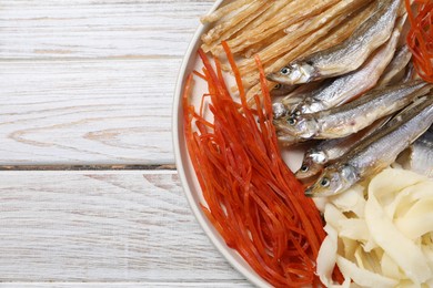 Many different dried fish snacks on white wooden table, top view. Space for text