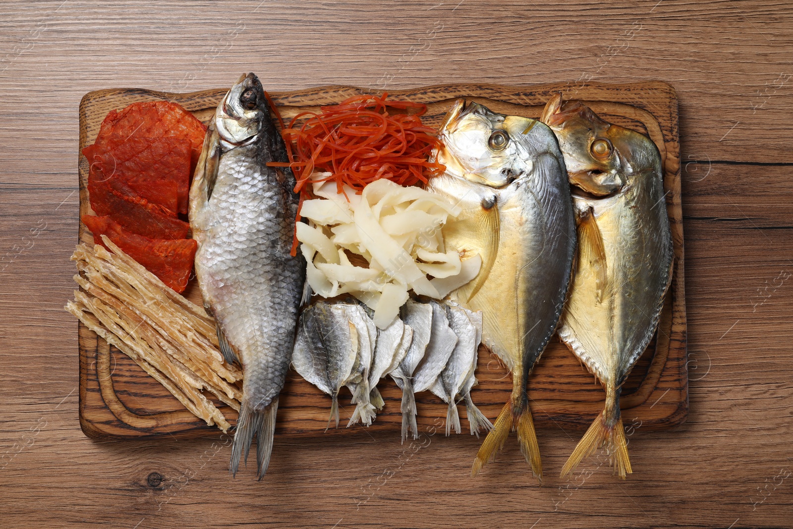 Photo of Many different dried fish snacks on wooden table, top view