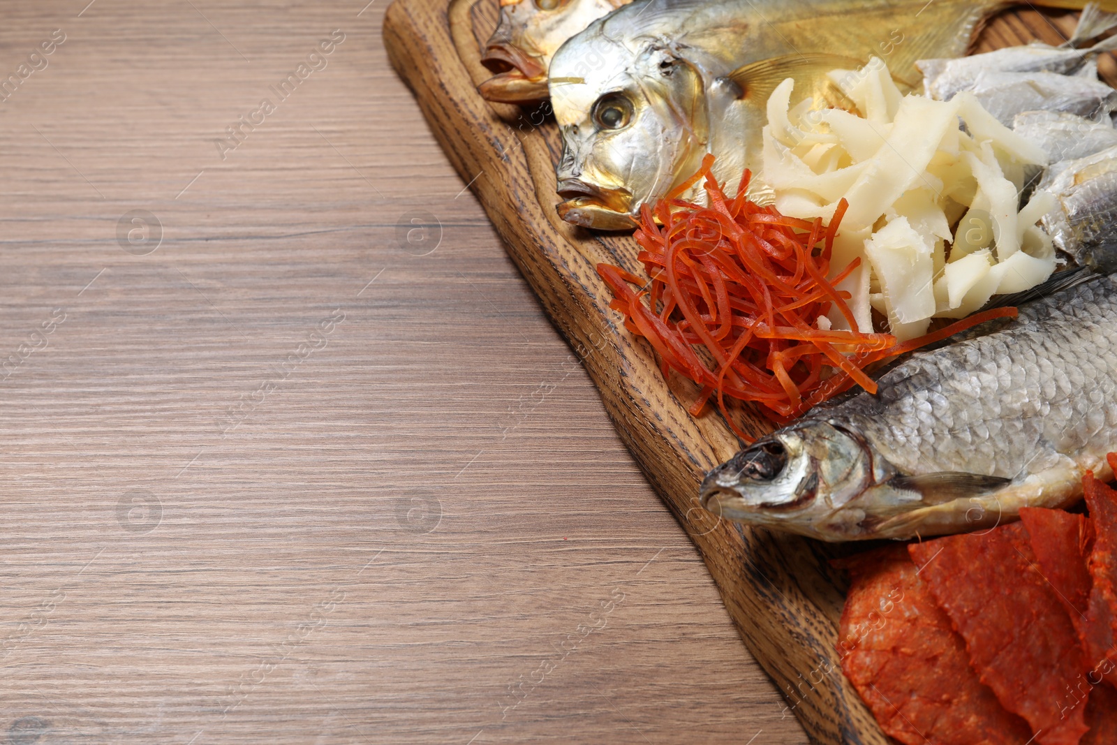 Photo of Many different dried fish snacks on wooden table, closeup. Space for text