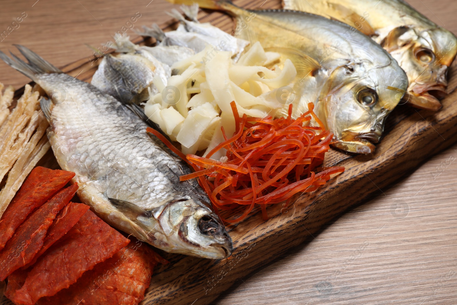 Photo of Many different dried fish snacks on wooden table, closeup