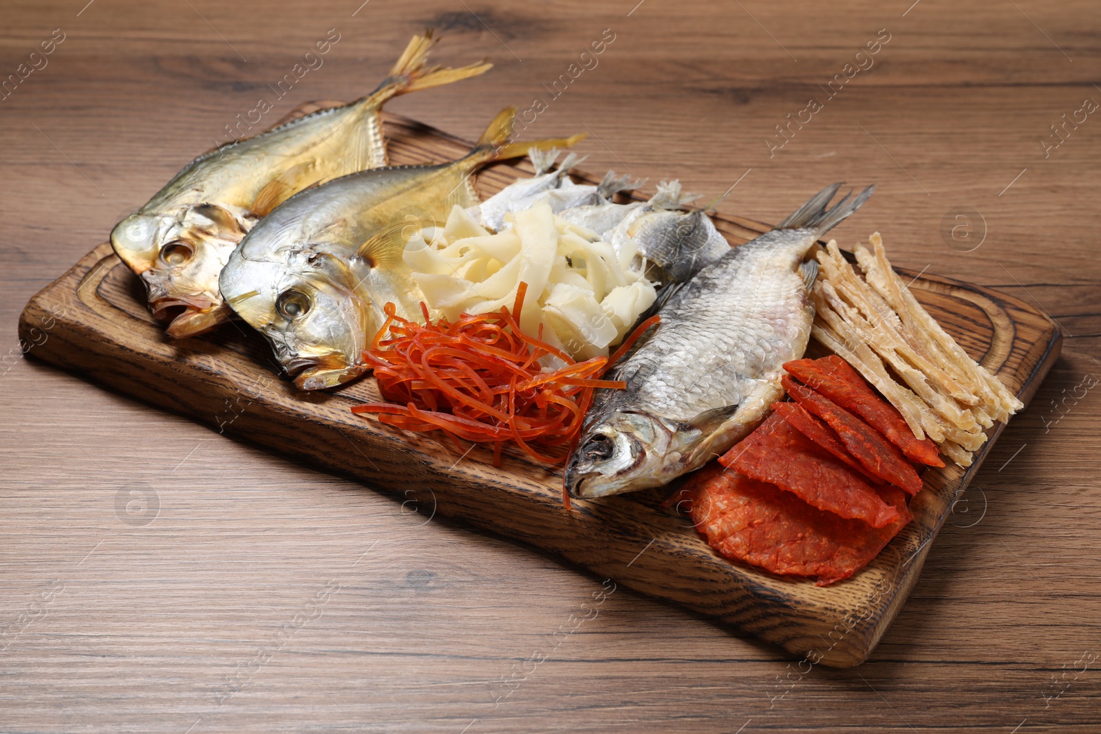 Photo of Many different dried fish snacks on wooden table